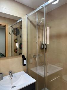 W łazience znajduje się szklana kabina prysznicowa i umywalka. w obiekcie Apartamento en Santiago Bernabéu w Madrycie