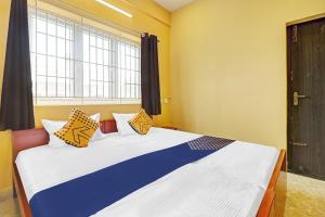 a bedroom with a large bed with colorful pillows at SPOT ON Kayal Residency in Coimbatore