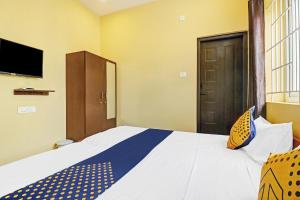 een slaapkamer met een groot bed en een televisie bij SPOT ON Kayal Residency in Coimbatore