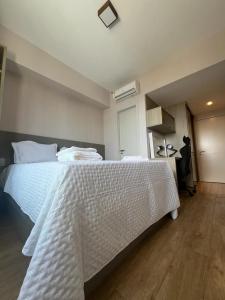 - une chambre avec un grand lit blanc et un bureau dans l'établissement Suíte Apart Hotel Mondial Salvador, à Salvador