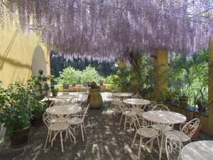 eine Terrasse mit Tischen und Stühlen unter lila Blumen in der Unterkunft Villanova - Nature & Wellness in Levanto