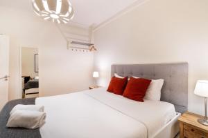 een slaapkamer met een groot wit bed met rode kussens bij Diario de Noticias by Central Hill Apartments in Lissabon