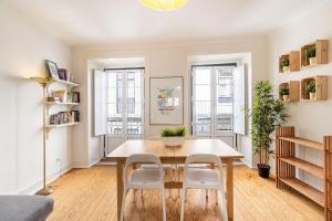 een eetkamer met een tafel en twee ramen bij Diario de Noticias by Central Hill Apartments in Lissabon