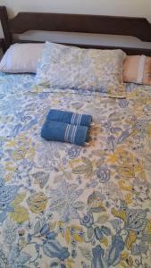 a bed with a blue and yellow bedspread with a pillow at Casa no paraíso Búzios! in Búzios