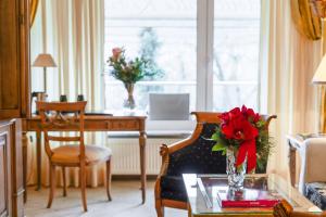 ein Wohnzimmer mit einem Tisch und einer Vase mit einer roten Blume in der Unterkunft Bernstein Hotel Villa Kastania in Berlin