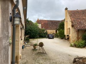 una calle con edificios y un coche aparcado en una entrada en La Ferme de Maraval, en Cénac-et-Saint-Julien