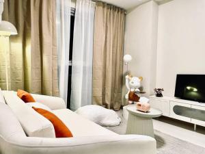 a living room with a white couch and a tv at Thompson Suites - 2-beds near OKADA, Bayshore 2 in Manila