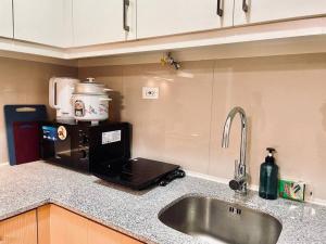 a kitchen counter with a sink and a microwave at Thompson Suites - 2-beds near OKADA, Bayshore 2 in Manila