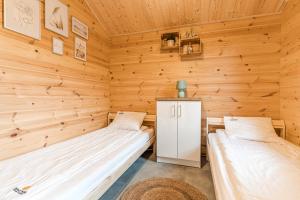 two beds in a room with wooden walls at Bursztynowo Mikoszewo in Mikoszewo