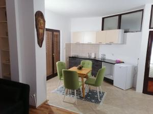 a kitchen and dining room with a table and green chairs at Apartment's DAMJAN - Kruševo in Kruševo
