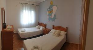 een kamer met twee bedden en een schilderij aan de muur bij La tranquila Manchuela in Alborea