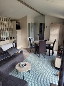 ein Wohnzimmer mit einem Sofa und einem Tisch in der Unterkunft Mobilhome tout confort, proche Saint-Malo, à 50 m de la plage et du GR34 in Saint-Coulomb