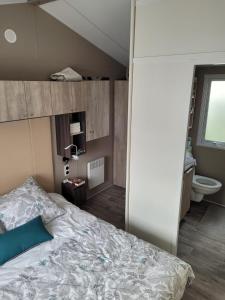 a bedroom with a large bed and a toilet at Mobilhome tout confort, proche Saint-Malo, à 50 m de la plage et du GR34 in Saint-Coulomb