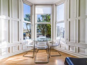 una mesa y sillas en una habitación con ventanas en Longsands Beach, Apartment 1, Tynemouth., en Tynemouth