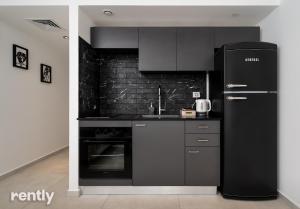 a kitchen with black appliances and a black refrigerator at Sea side "Marigold" apartment - by Rently in Eilat