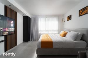 a white bedroom with a bed and a tv at Sea side "Marigold" apartment - by Rently in Eilat