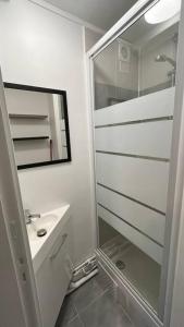uma casa de banho branca com um lavatório e um espelho em Appartement Porte de Vincennes Nation - 2 pers em Saint-Mandé
