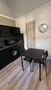 uma mesa preta num quarto com uma mesa e uma cozinha em Appartement Porte de Vincennes Nation - 2 pers em Saint-Mandé