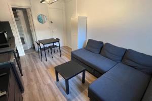 uma sala de estar com um sofá azul e uma mesa em Appartement Porte de Vincennes Nation - 2 pers em Saint-Mandé