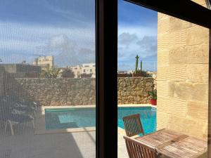 een raam met uitzicht op een zwembad bij 4 Bedroom Holiday Home with Private Pool & Views in Xewkija