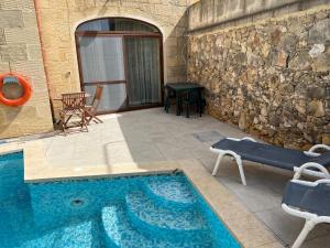 a swimming pool with a table and chairs next to a building at 4 Bedroom Holiday Home with Private Pool & Views in Xewkija