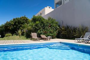 uma piscina com duas cadeiras ao lado de um edifício em Vitaminas - Casa de Playa y Café em Punta del Este