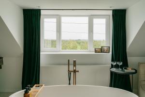 uma casa de banho com uma banheira e uma janela em MAM Haspengouw em Sint-Truiden