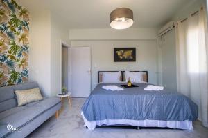 ein Schlafzimmer mit einem blauen Bett und einem Sofa in der Unterkunft 'Ariadni' Elegant Residence in Athen