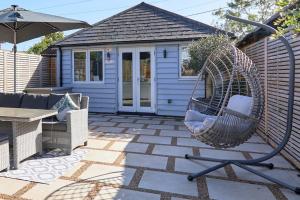 a swinging chair on a patio with a house at The Sea House Beautiful Large Whitstable Home With Sea Views in Kent
