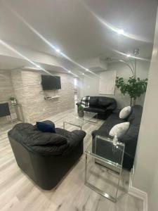 sala de estar con sofá negro y TV en Luxurious & upscale basement apartment, en Brampton