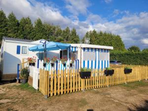 una cerca con un paraguas azul y una casa en L'ESCALE, en Le Bec-Hellouin