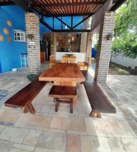 une grande table en bois et des bancs sur une terrasse dans l'établissement Suíte quádrupla Odoyá Beach, à Conde