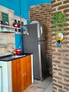 a kitchen with a refrigerator next to a brick wall at Suíte quádrupla Odoyá Beach in Conde