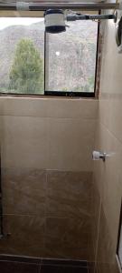 a bathroom with a window and a tiled shower at Casa de George in Urubamba