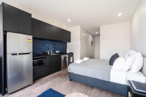 sypialnia z łóżkiem oraz kuchnia z lodówką w obiekcie Hanover Apartment No 1 w mieście Dunedin