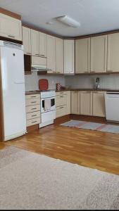 uma cozinha vazia com electrodomésticos brancos e pisos em madeira em Paritalokolmio joen rannalla em Haapavesi