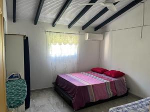 Un dormitorio con una cama con almohadas rojas y una ventana en haut de villa spacieux et calme, en Morne-à-lʼEau