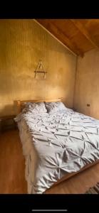an unmade bed in a bedroom with a wooden ceiling at Cabaña cercana a bosque nativo Frutillar in Puerto Octay