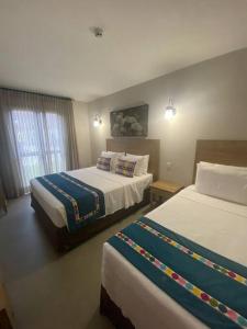 ein Hotelzimmer mit 2 Betten und einem Fenster in der Unterkunft Eco Resort Quinta Santa Bárbara Ap 101/11 bloco E in Pirenópolis