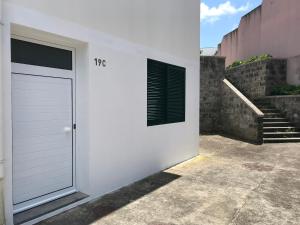 une porte de garage blanche avec une fenêtre et des escaliers. dans l'établissement Ninho do Monte, à Ponta Delgada