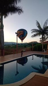 a hot air balloon flying over a swimming pool at Agencia e Pousada - Capitolio - MG in Capitólio