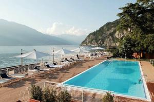 a swimming pool with chairs and umbrellas next to the ocean at Green House Olivedo in Varenna