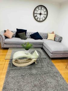 a living room with a couch and a clock on the wall at The Hamilton Gated 2Bedroom Annex Dartford in Darenth