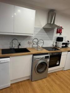 a kitchen with white cabinets and a washing machine at The Hamilton Gated 2Bedroom Annex Dartford in Darenth