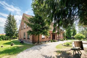 a brick building with a tree in front of it at Dworek Mazurski Ruś in Ruś