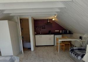 Cette chambre mansardée comprend une cuisine et une table. dans l'établissement Plieņciems Urgas apartamenti 2. stāvā, à Plieņciems