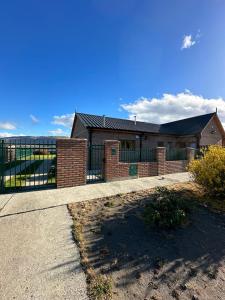 a brick building with a fence in front of it at Casa 48 in El Calafate