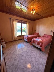 a room with two beds and a large window at Casa 48 in El Calafate