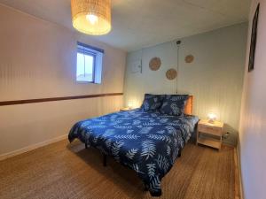 een slaapkamer met een blauw bed en een raam bij L'Expo in Hénin-Beaumont