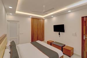 een slaapkamer met een bed en een flatscreen-tv bij Super Collection O Hotel Spot Light Near Tughlakabad Station Metro Station in Indraprastha